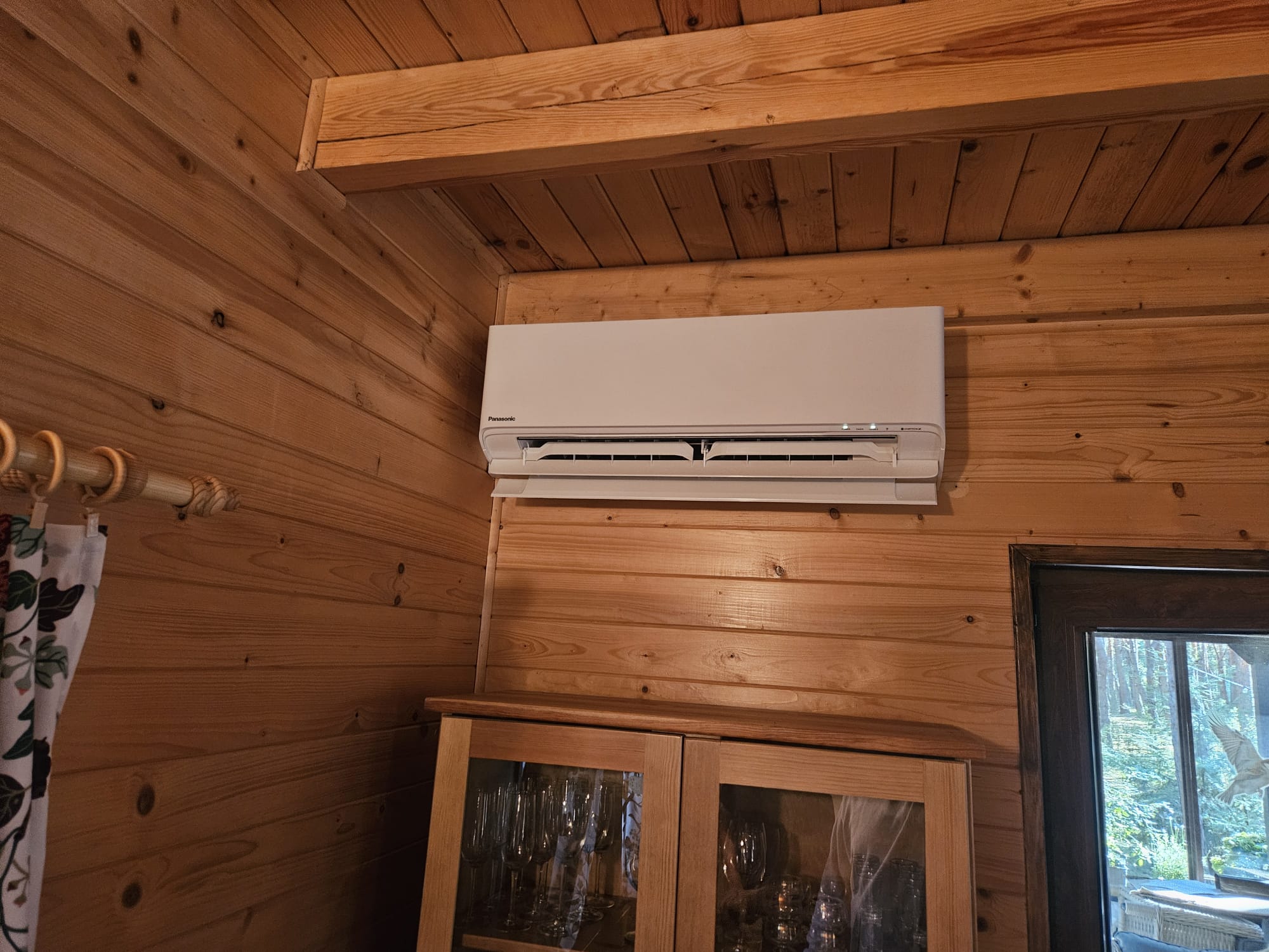 Biały Klimatyzator naścienny Panasonic na przytulnym ciemnym drewnianym tle