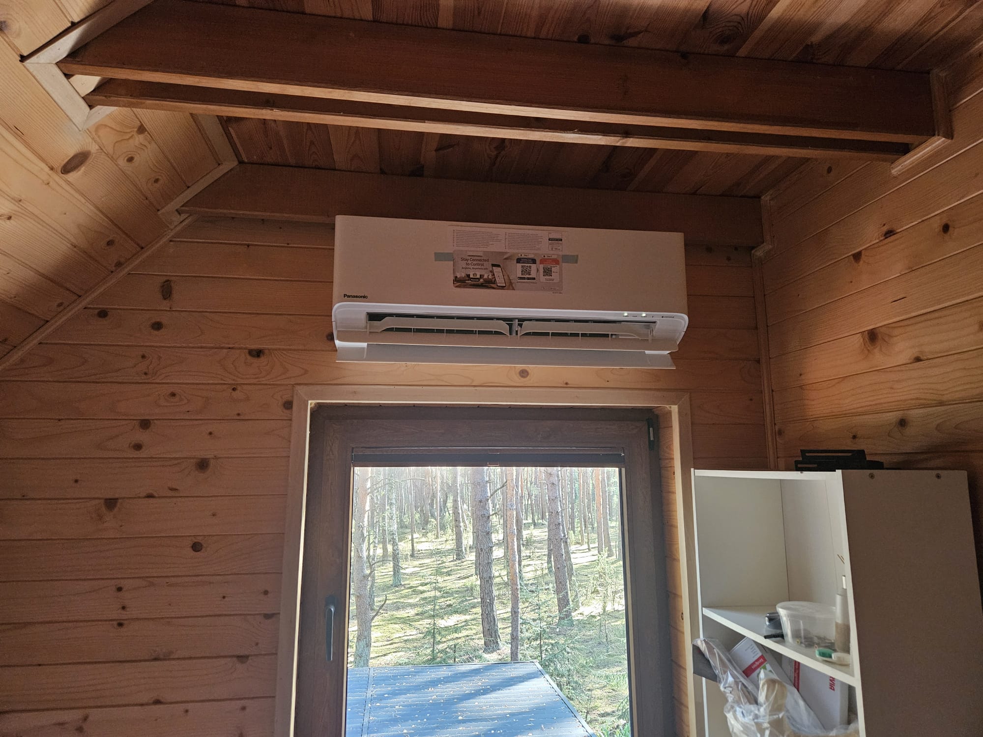 Biały Klimatyzator naścienny Panasonic na przytulnym jasnym drewnianym tle