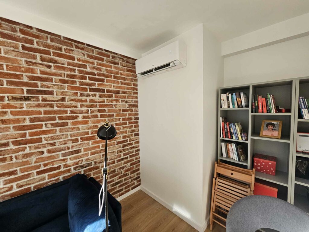 Pokój z ceglaną ścianą, półką na książki i klimatyzacją