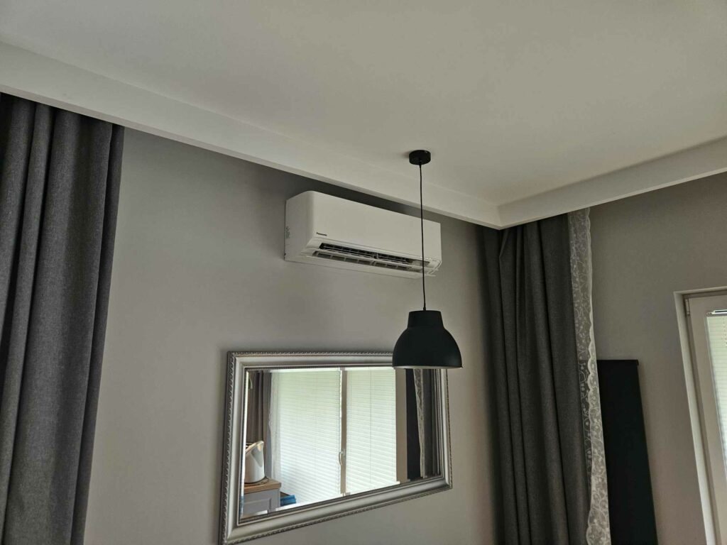 Klimatyzator na ścianie pokoju z lampą.